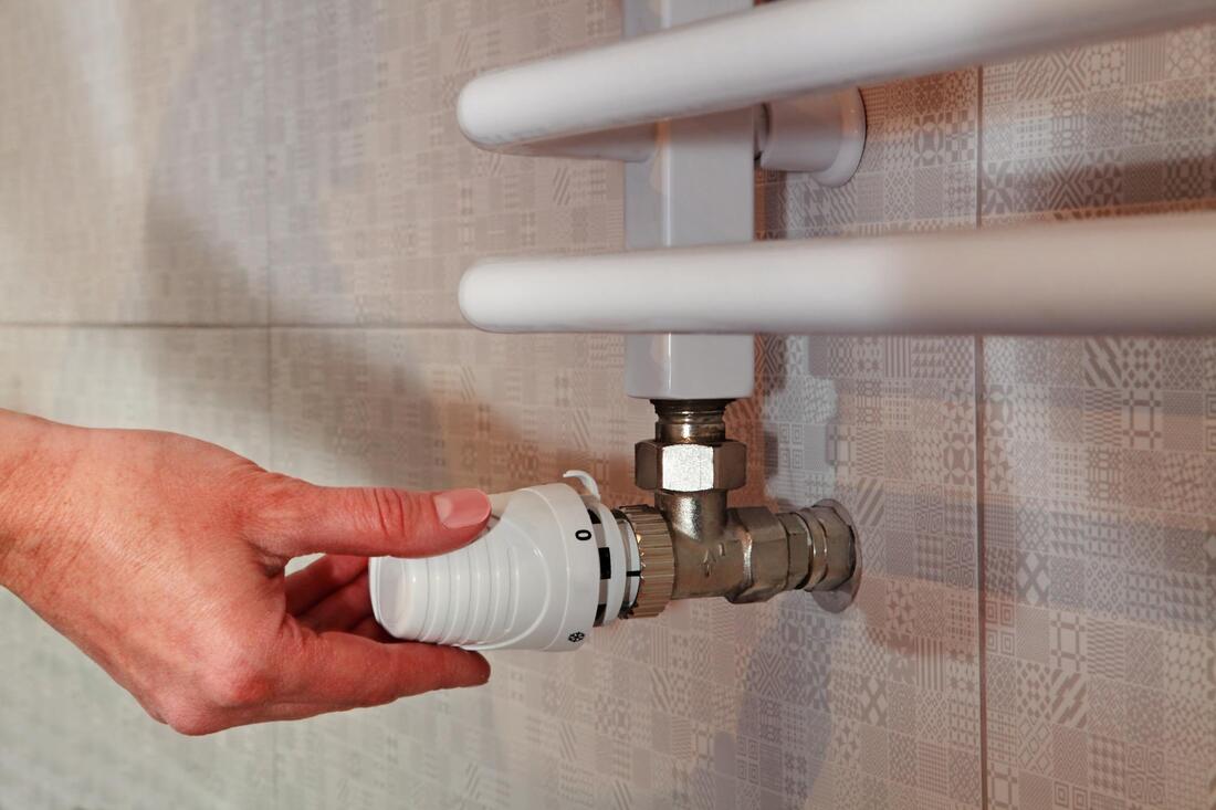 A person is adjusting a thermostat on a radiator.
