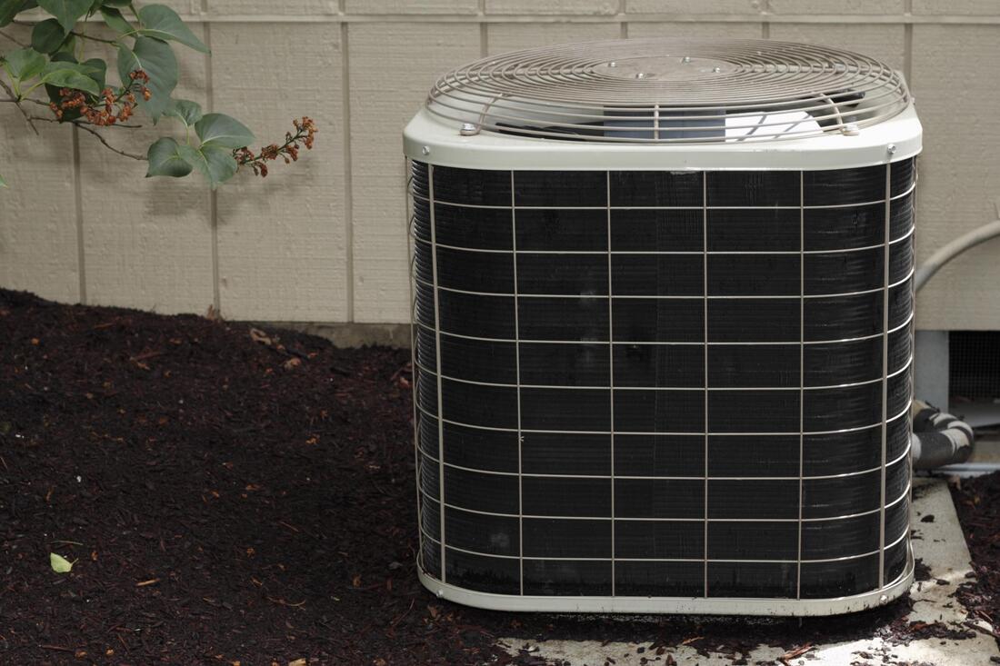 A black and white air conditioner is sitting on the ground