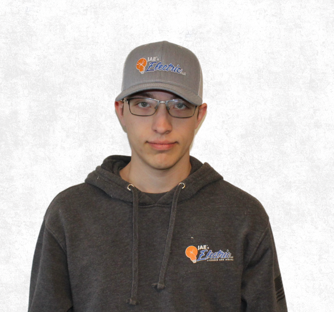 Person wearing a gray hoodie and cap, standing against a plain white background.