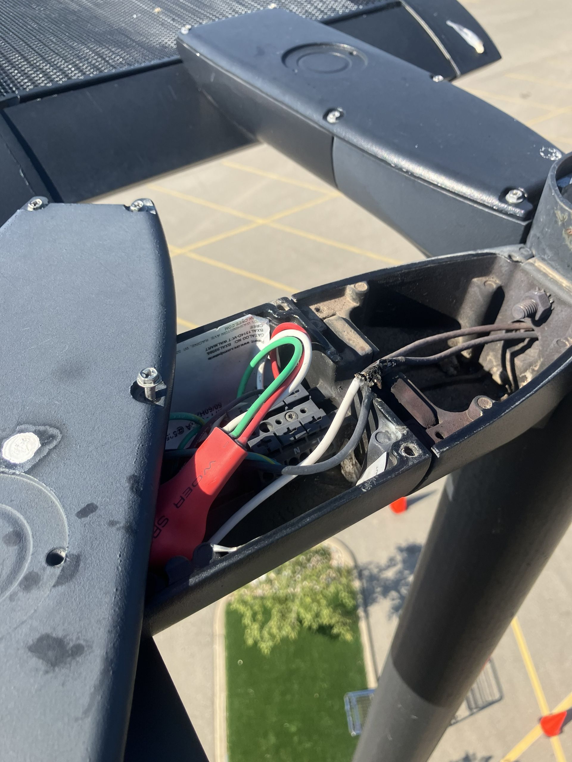 Close-up of a damaged black drone arm with exposed red, green, and black wires.