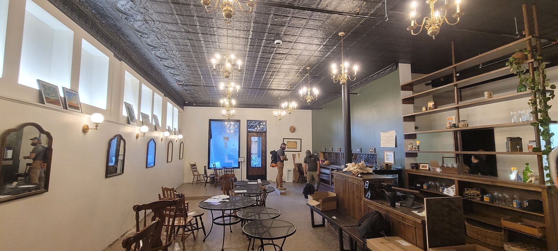 Cozy café interior with small tables, mirrors, shelves, and ornate ceiling lights