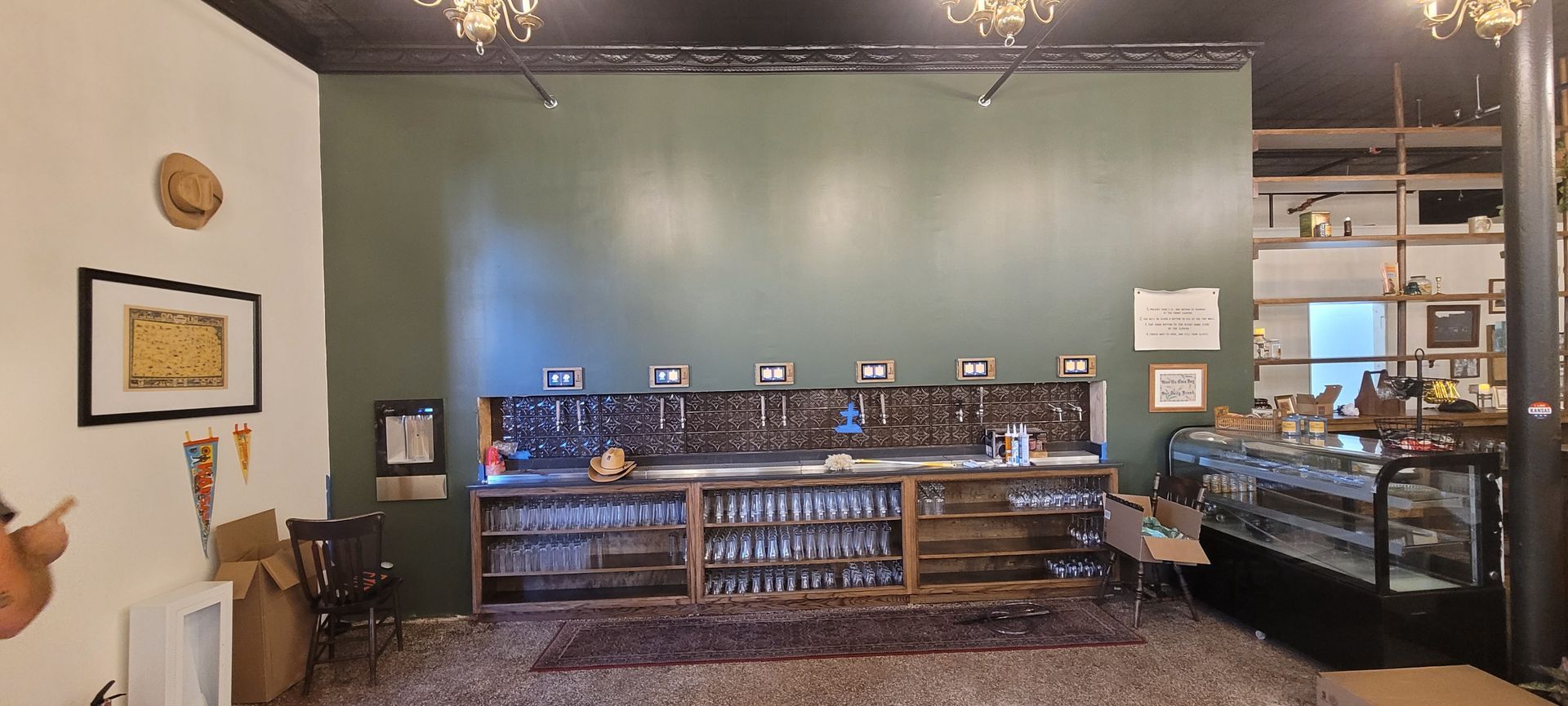 Cozy café interior with a green wall, counter seating, and pastry display case