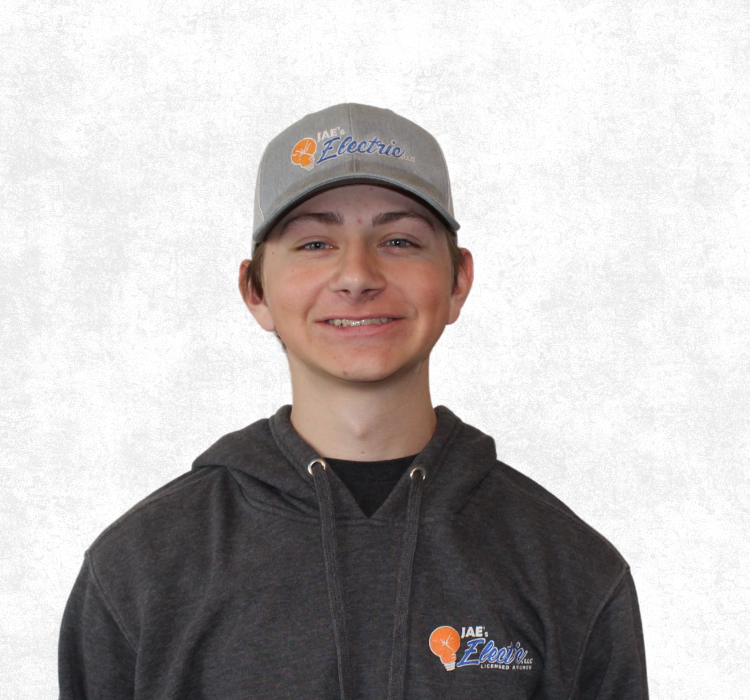 Smiling person in a gray cap and dark hoodie against a light gray background