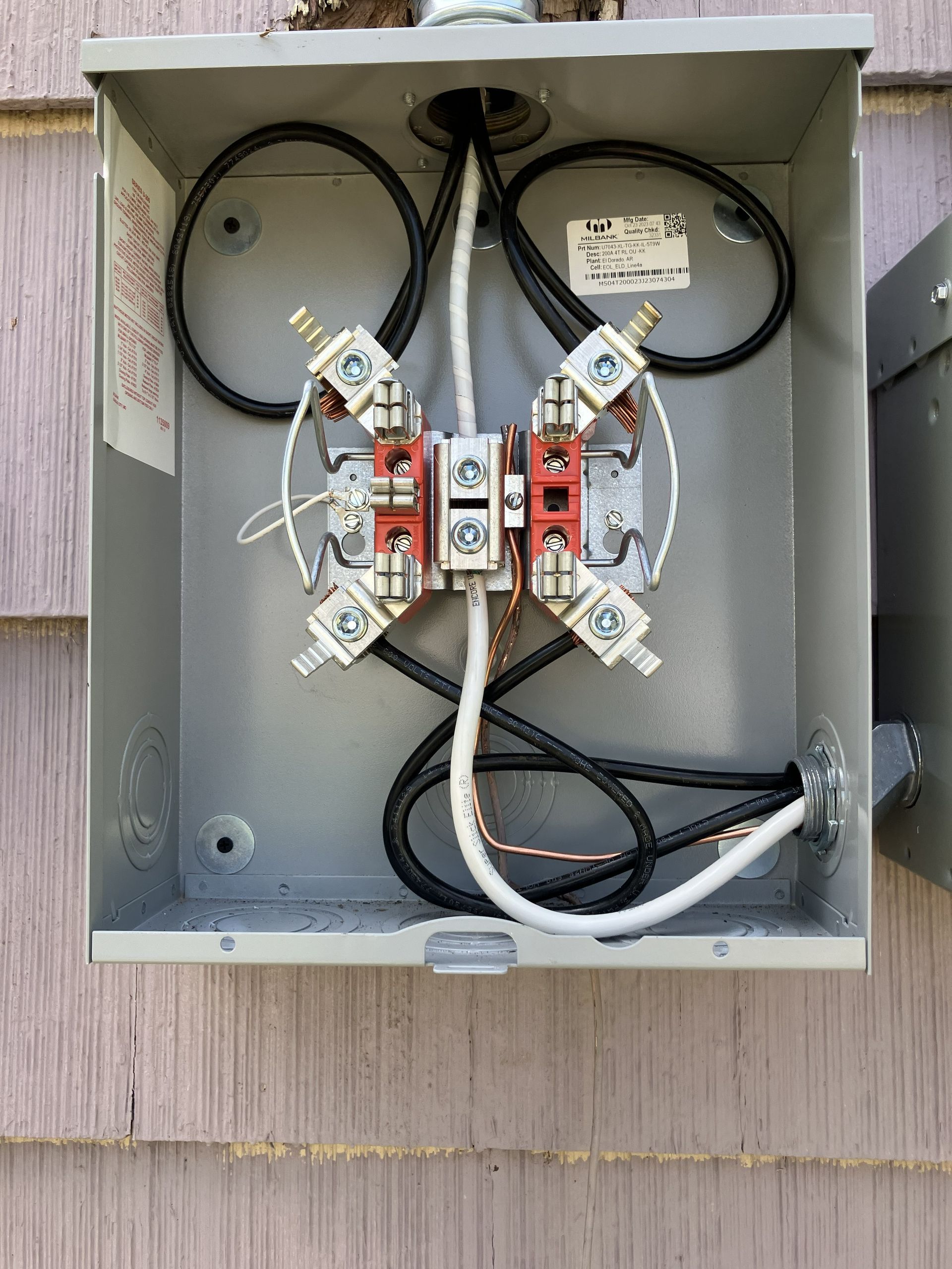 Open electrical panel with exposed wiring and terminal blocks mounted on a gray wall