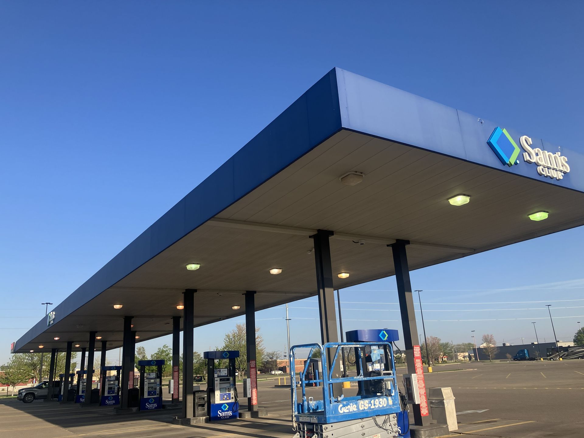 Gas station canopy with blue trim at dusk, featuring pumps and a convenience store sign.