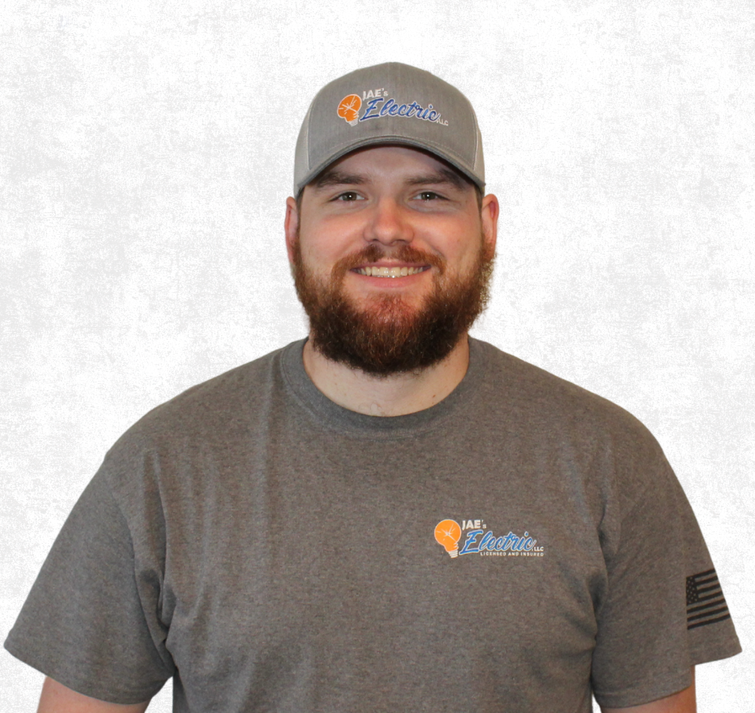 Smiling man in gray T-shirt and cap standing against a white background