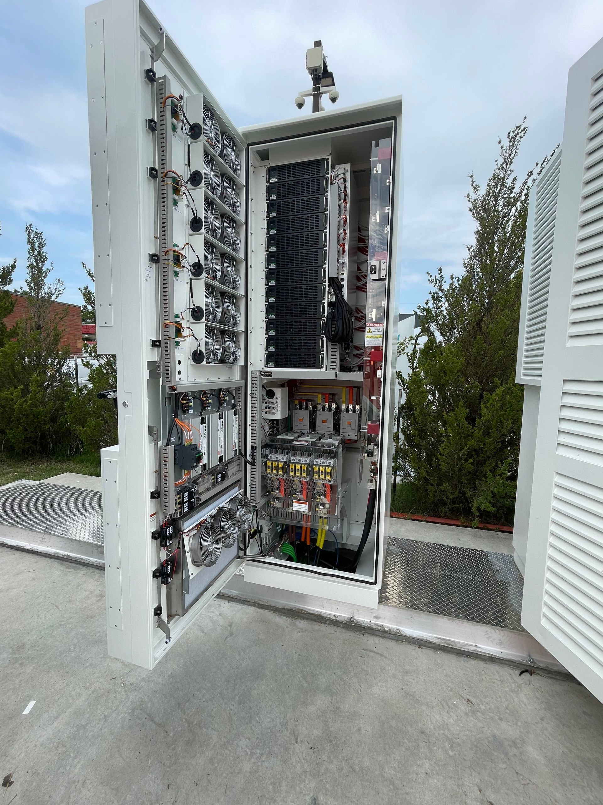 Open electrical control cabinet outdoors with exposed wiring and components