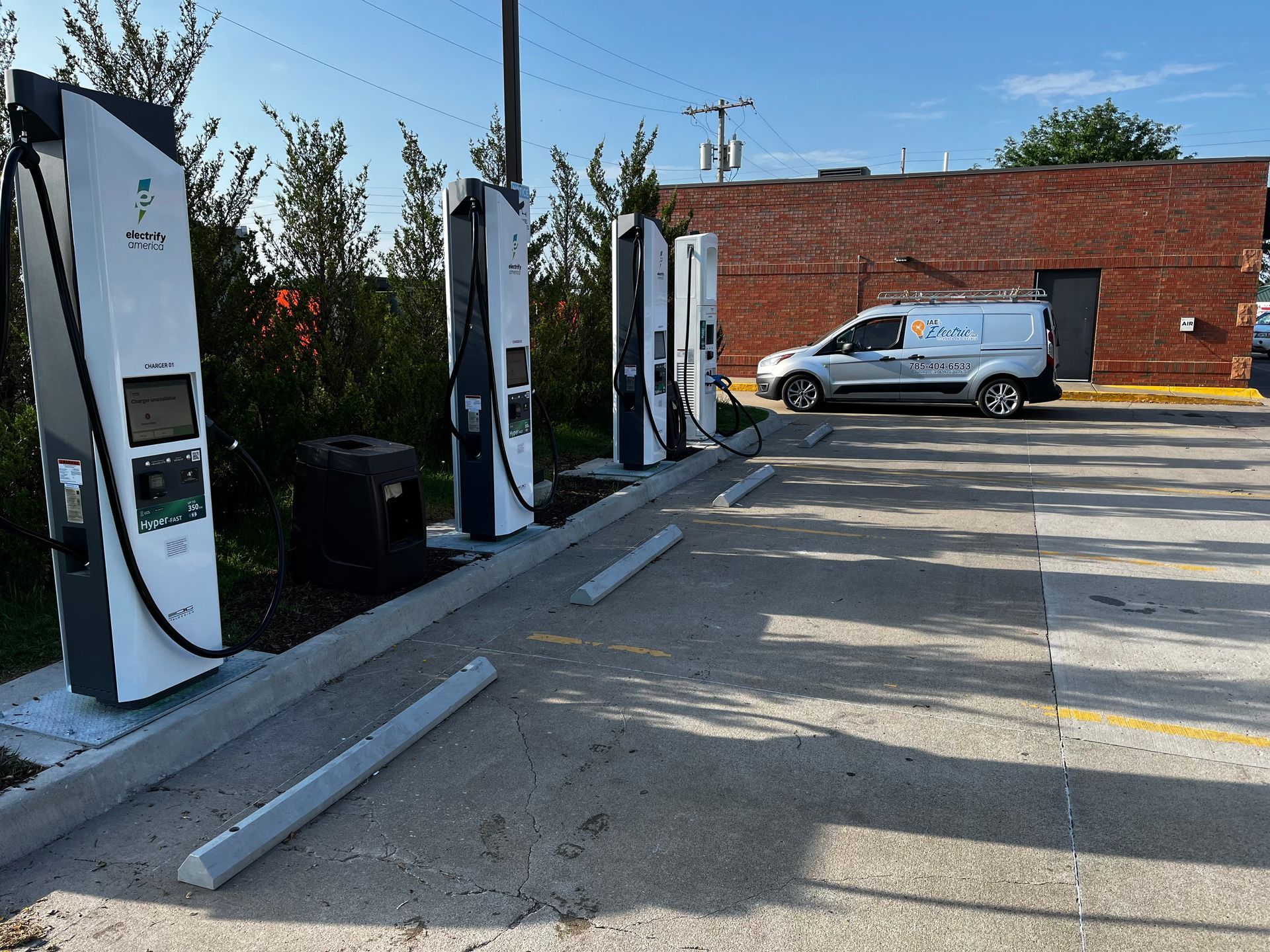 EV charging stations in a parking lot beside a brick building and parked van.