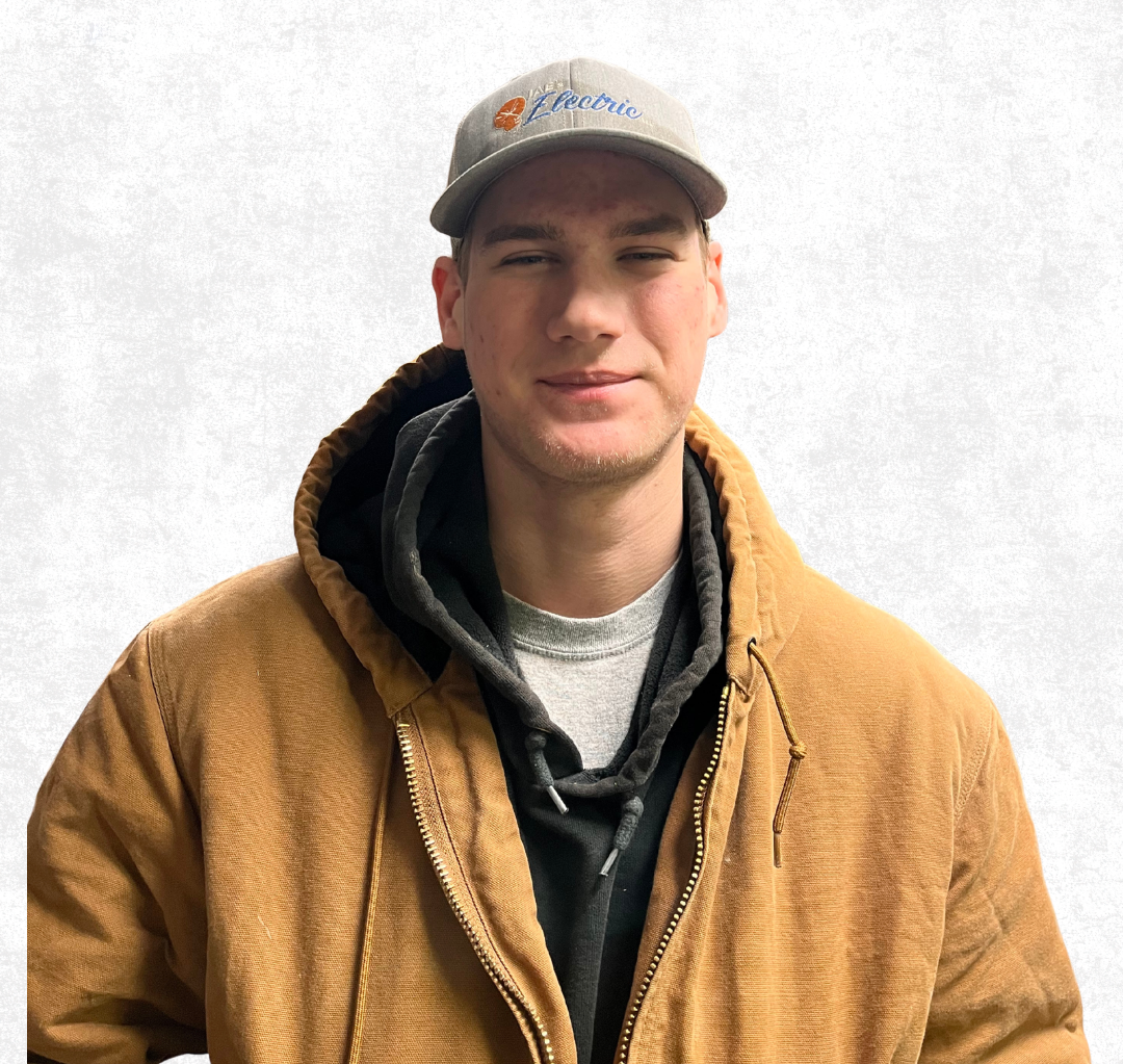 Person in a tan jacket and gray cap standing against a white background.