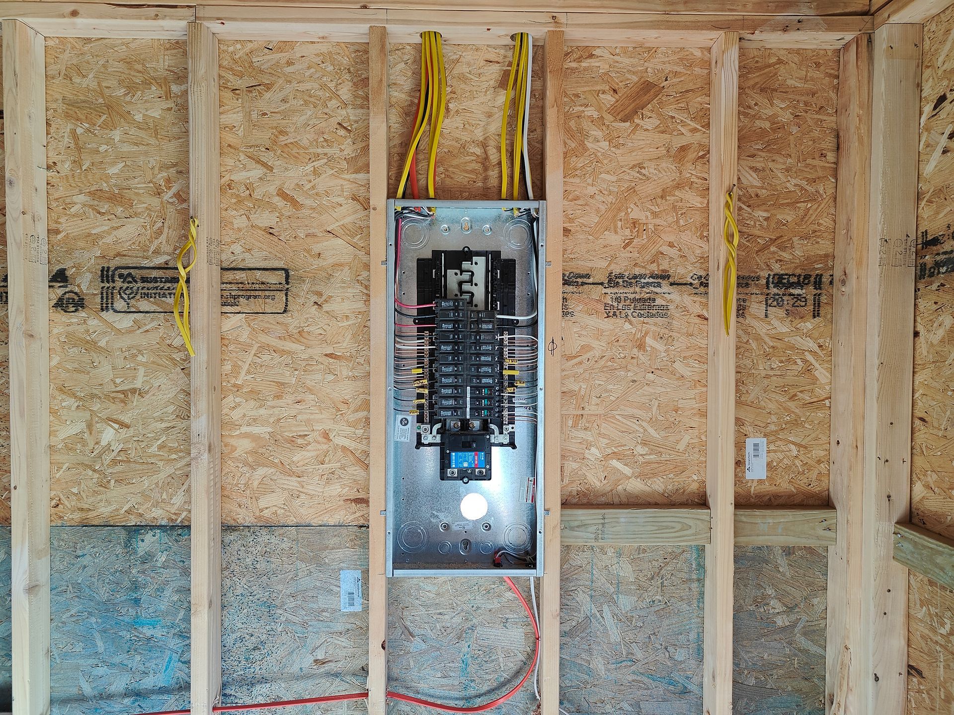 Electrical panel mounted on unfinished wall framing with exposed wires