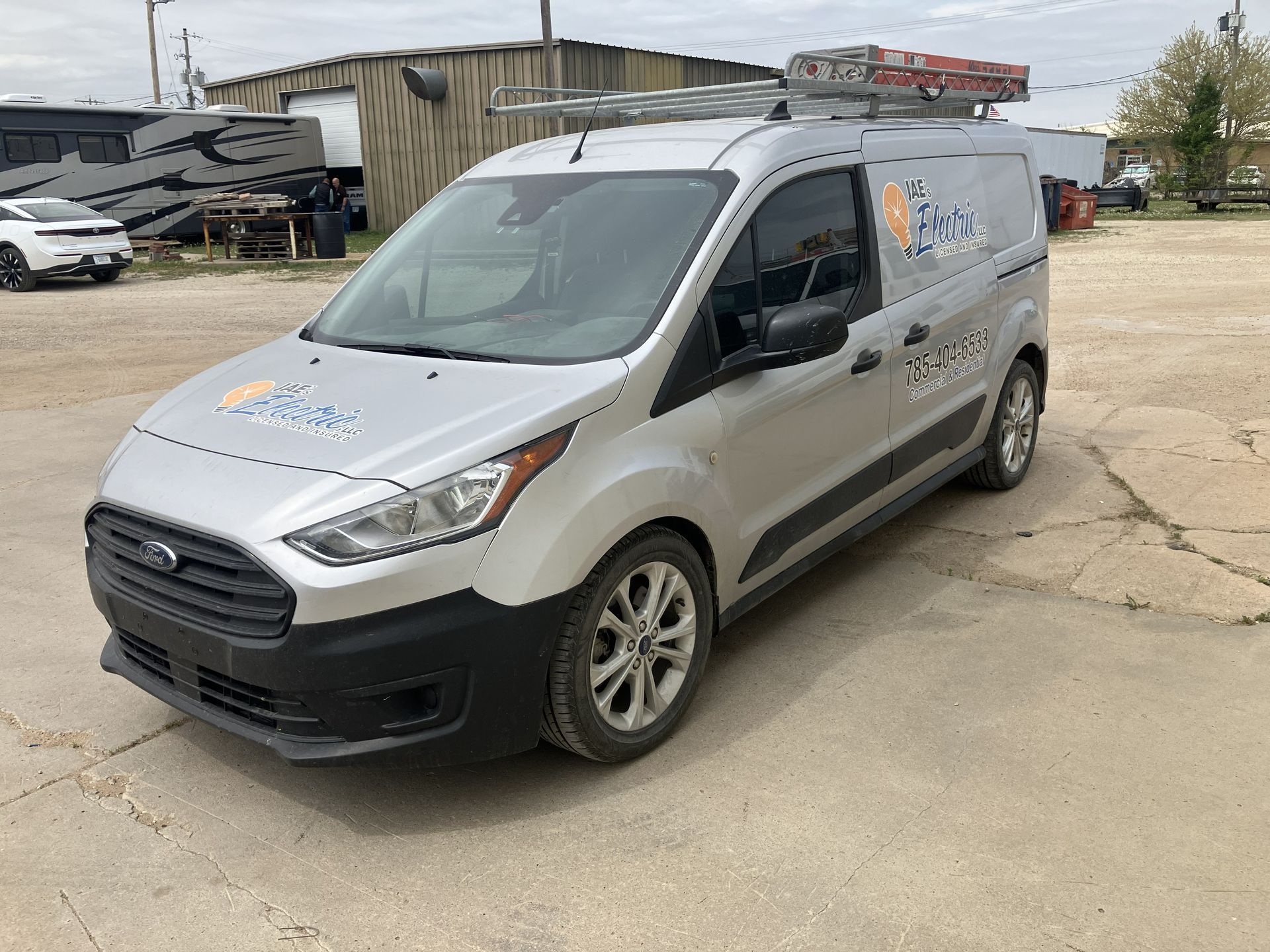 White cargo van with company decals parked on a gravel lot near buildings