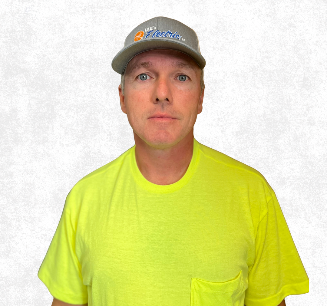 Man in gray cap and neon yellow T-shirt standing against a plain white background