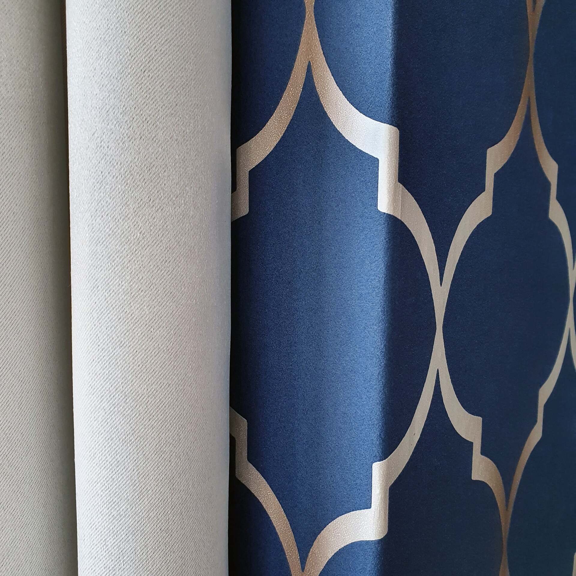 Een licht crèmekleurig gordijn dat perfect past bij een donkerblauw behang met een crèmekleurig geometrisch patrron