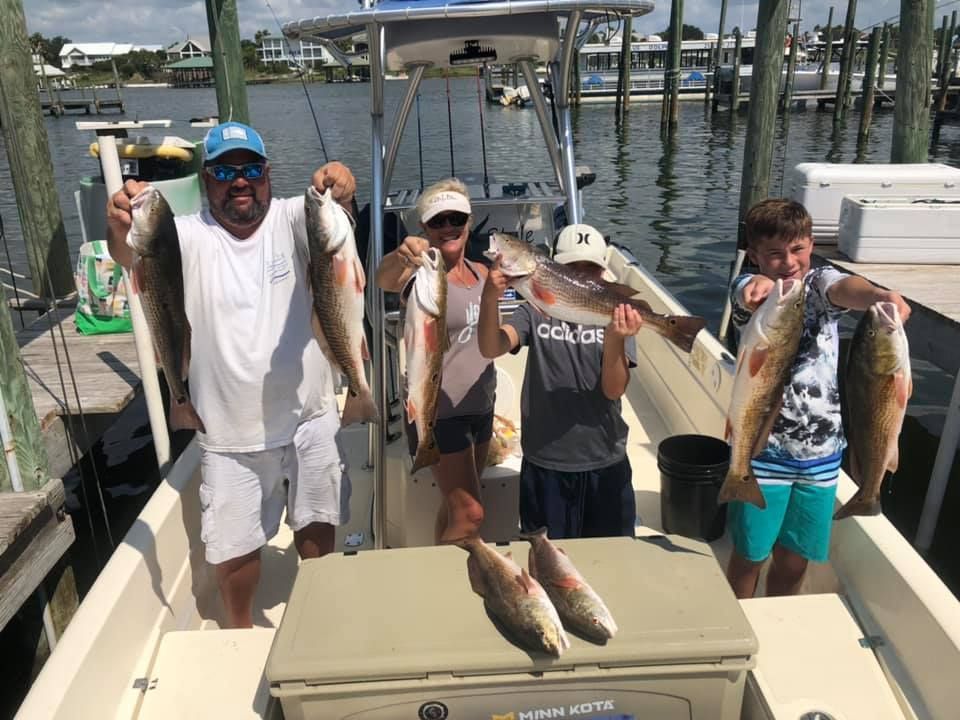 A group of people are standing on a boat holding fish.