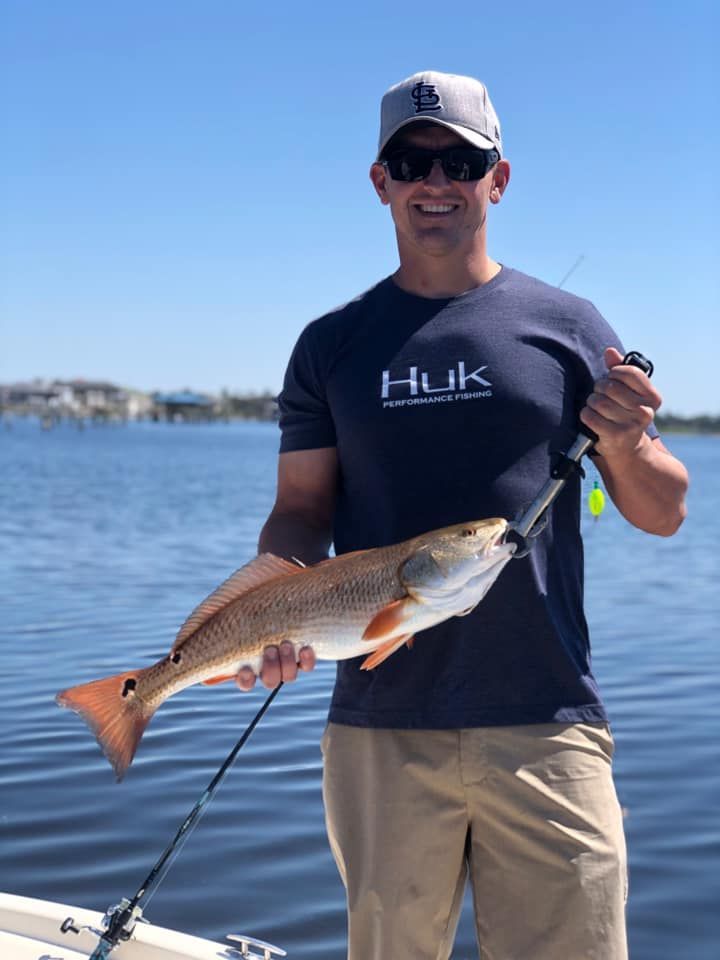 A man in a hulk shirt is holding a fish in his hands.