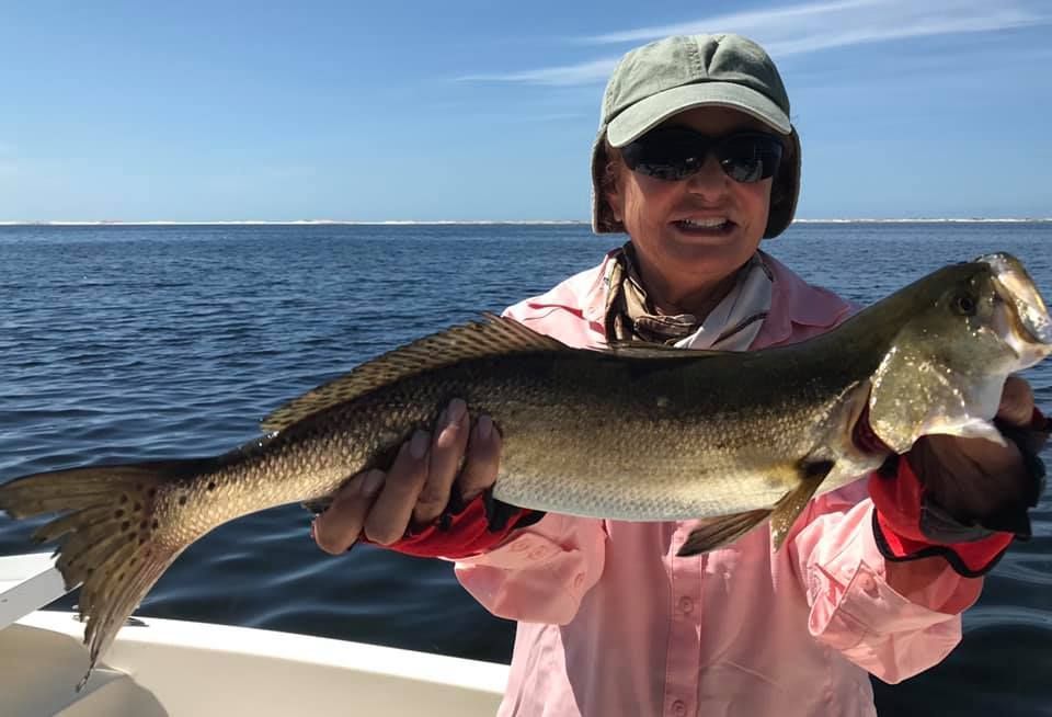 A woman is holding a large fish on a boat in the ocean.