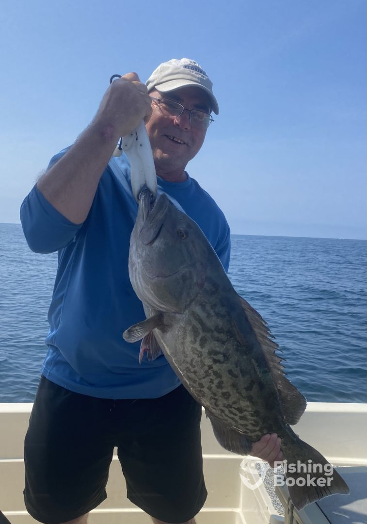 A man is holding a large fish on a boat.