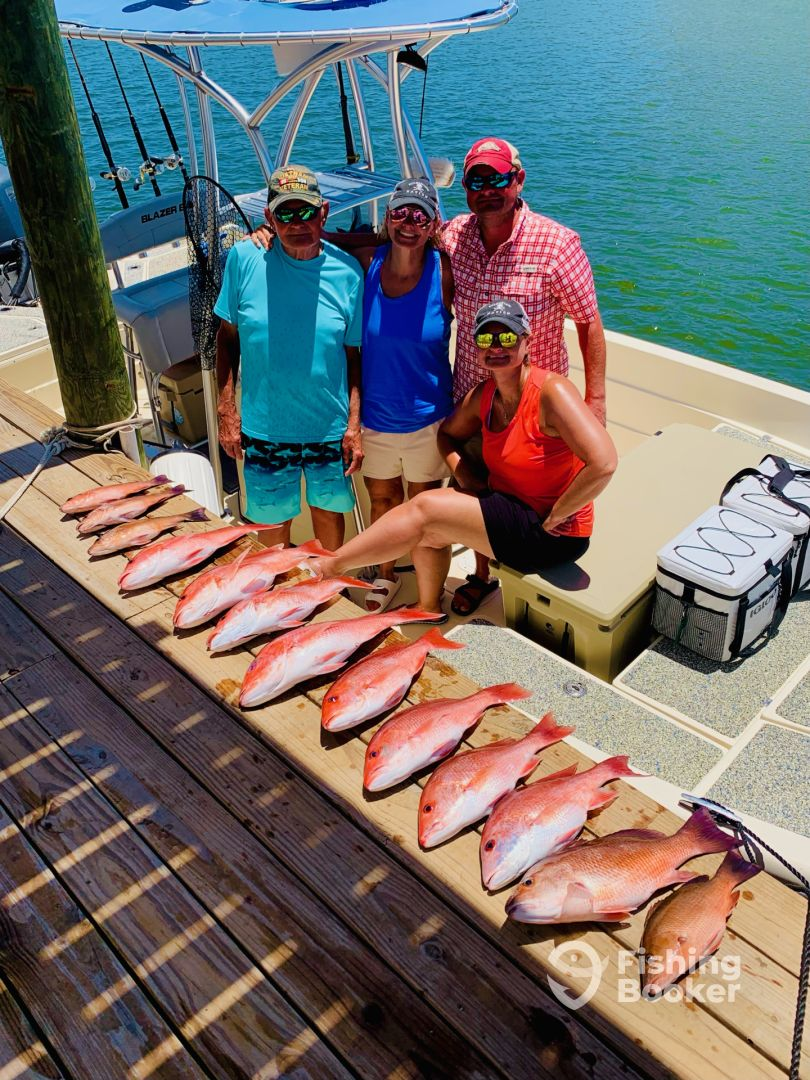 A group of people are standing on a dock next to a boat filled with fish.