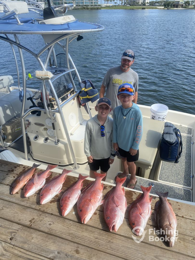 A man and two boys are standing on a boat with a bunch of fish.