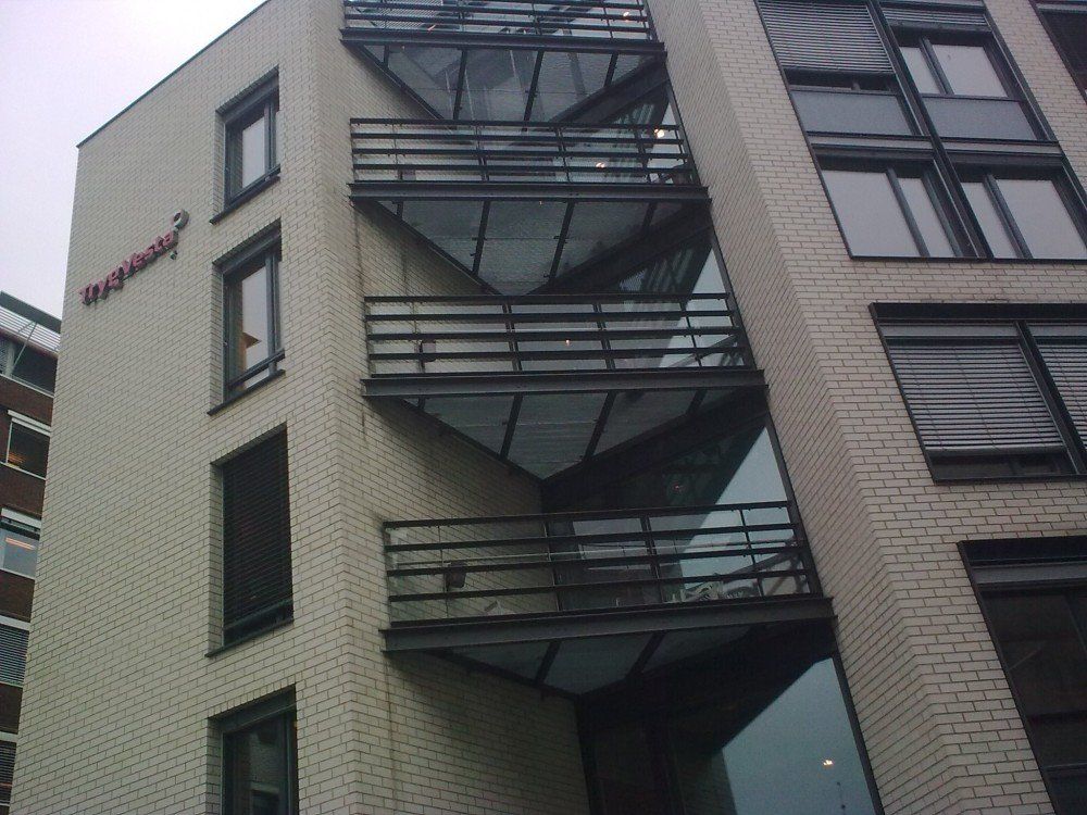 Moderne leilighetsbygg med geometriske balkonger og en lys mursteinsfasade.