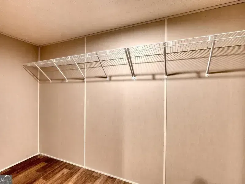 Empty walk-in closet with wire shelving and beige walls, viewed from the corner.