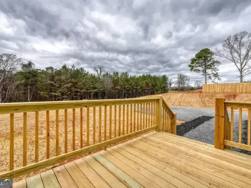 Wooden deck overlooking a fenced backyard with bare trees and a gravel path