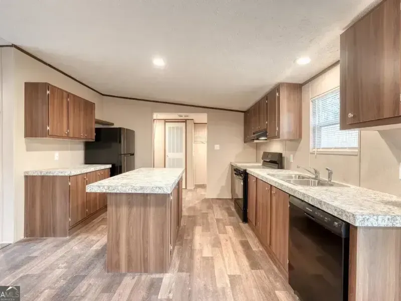 Modern kitchen with wood cabinets, granite counters, central island, and black appliances