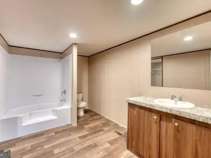 Modern bathroom with bathtub, toilet, and wood vanity with large mirror