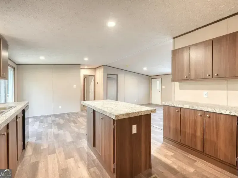 Bright open kitchen and living area with wood cabinets, granite island, and light wood floors