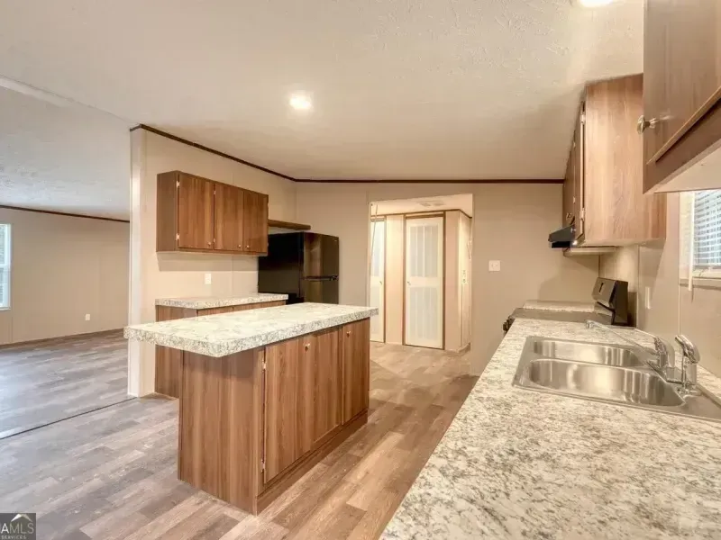Spacious kitchen with wood cabinets, granite countertops, island, and stainless steel sink and appliances