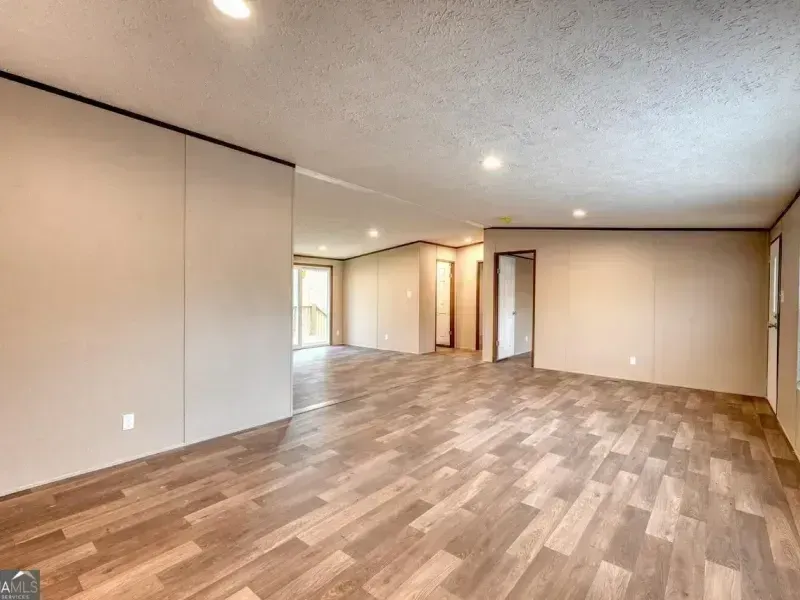 Empty beige living room with wood flooring and recessed ceiling lights