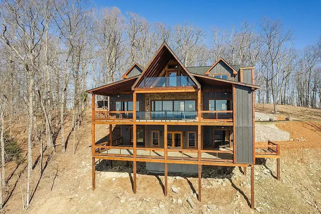 Partially built wooden house on a hillside with leafless trees in the background