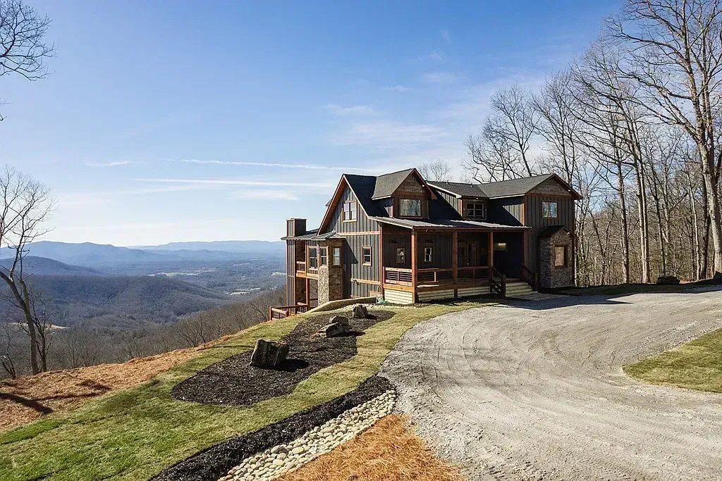 Large house on a hilltop overlooking a wide valley under a clear blue sky.