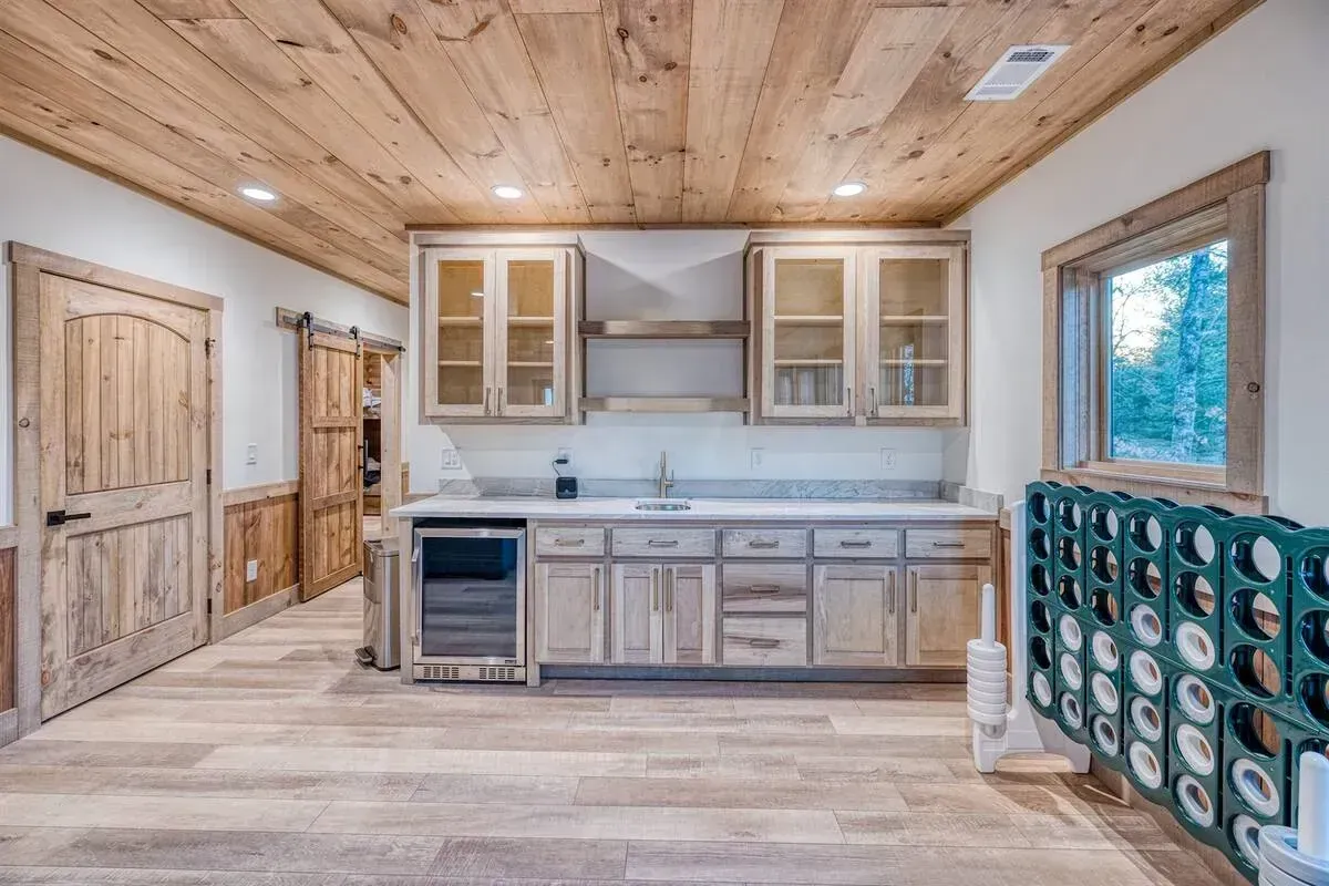 Rustic kitchen with wood ceiling, light cabinets, and blue tile backsplash in a small cabin interior