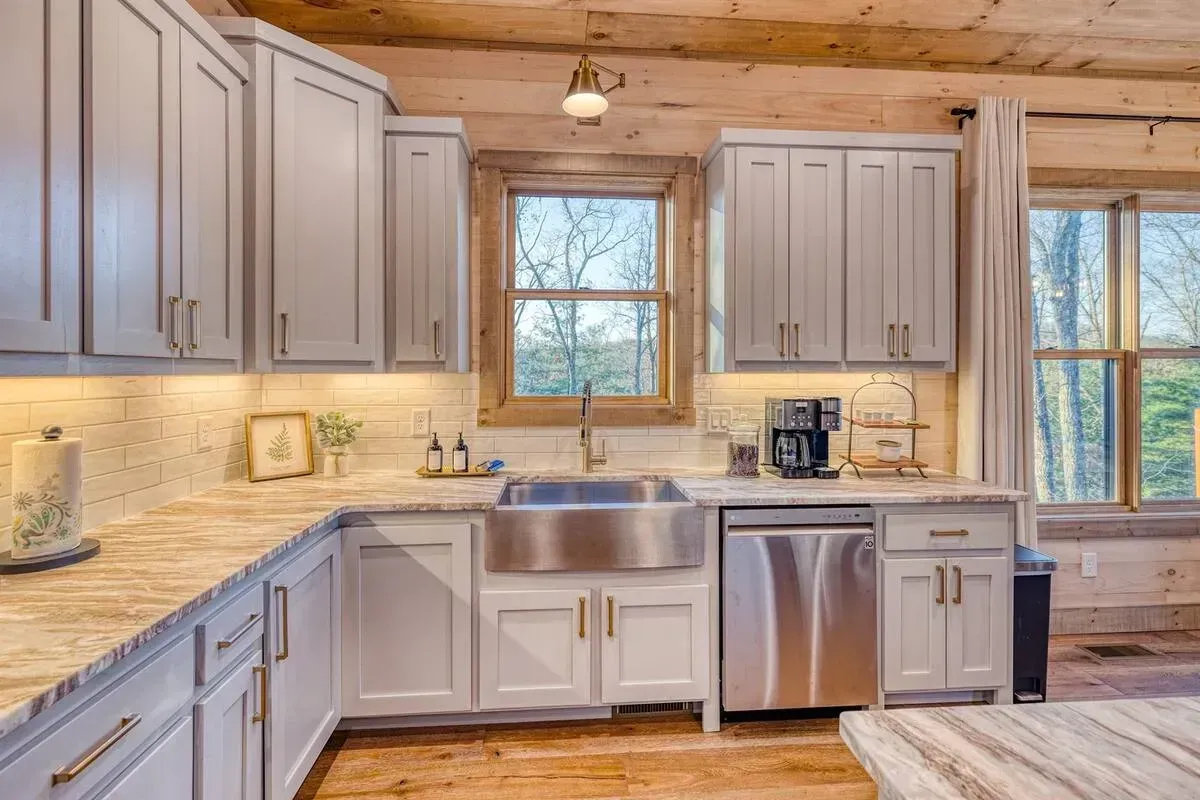 Bright rustic kitchen with gray cabinets, stainless appliances, wood ceiling, and large windows