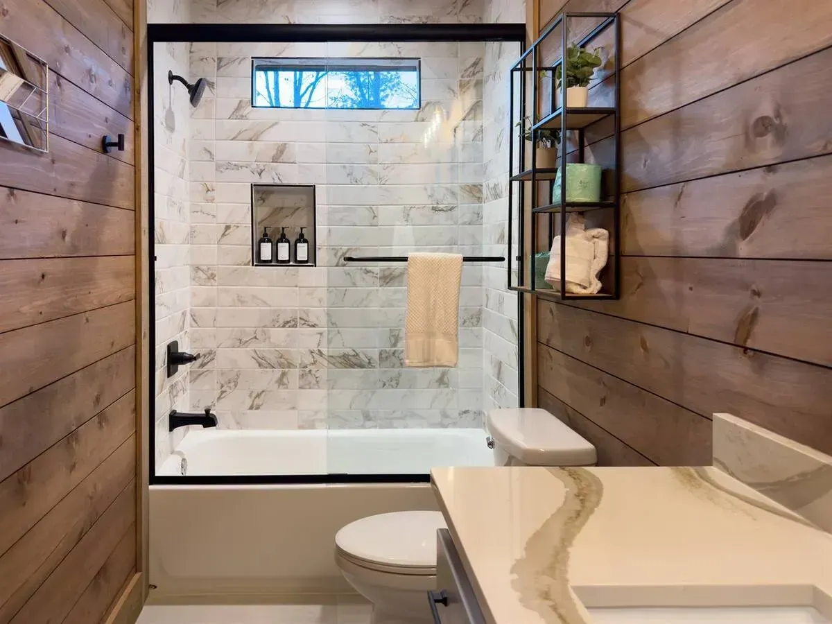 Modern bathroom with wood walls, marble shower, glass enclosure, and a beige vanity.