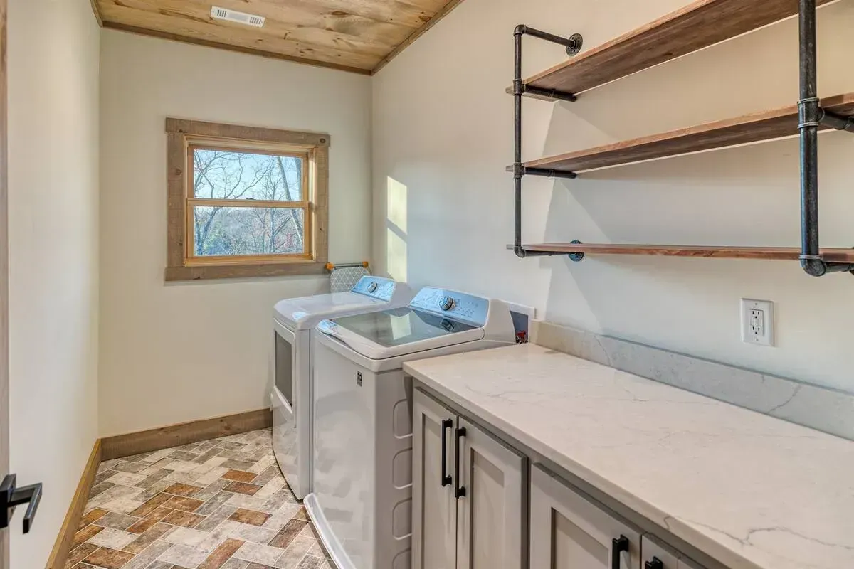 Laundry room with washer, countertop cabinets, open shelves, and a small window