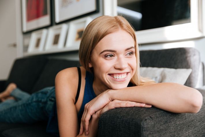 A woman is laying on a couch and smiling.
