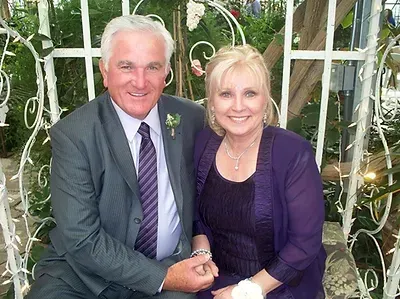 A man in a suit and tie is sitting next to a woman in a purple dress.