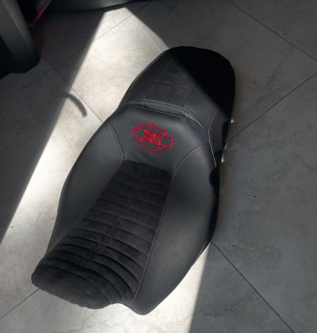 Black scooter seat with red logo on a tiled floor in sunlight