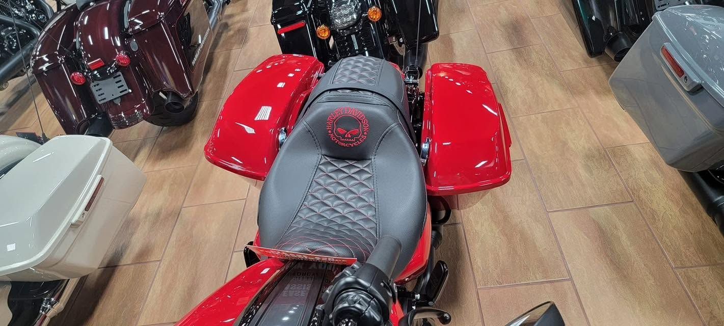 Red motorcycle in a showroom, viewed from above, with other scooters and bikes around it.