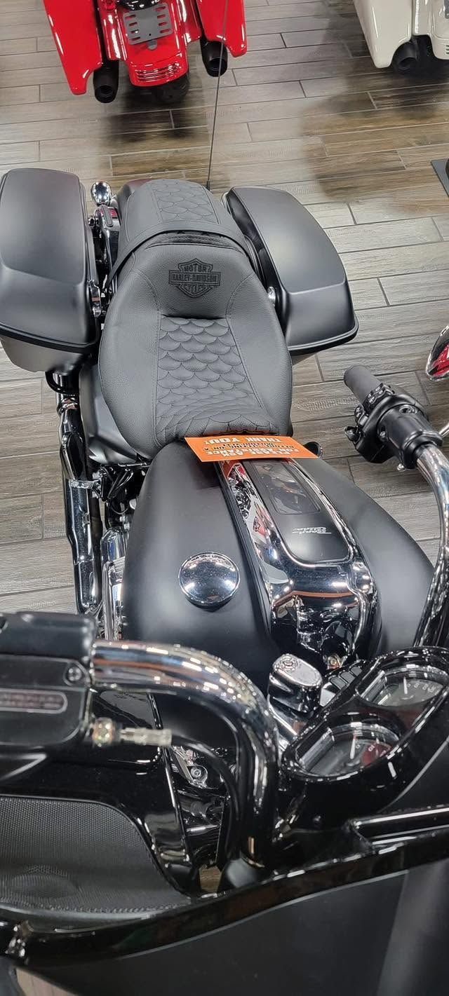Black motorcycle with a textured seat in a garage, viewed from above.