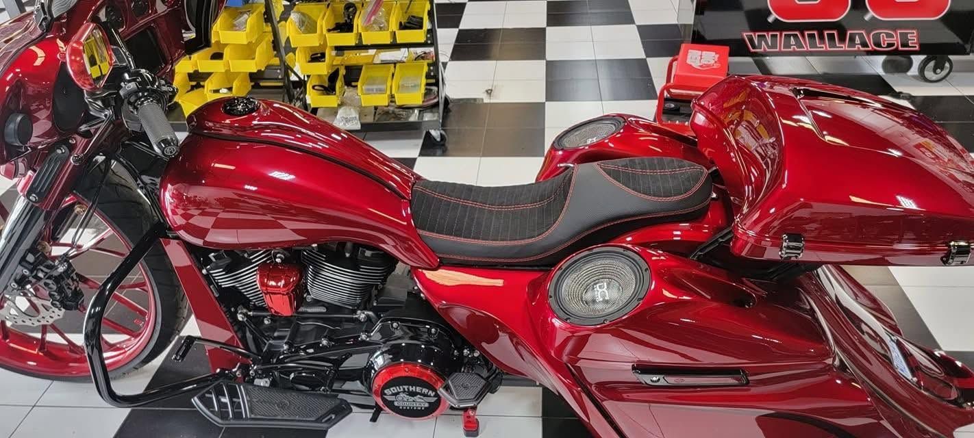 Red custom motorcycle on a showroom floor with checkered tiles and yellow bikes in the background