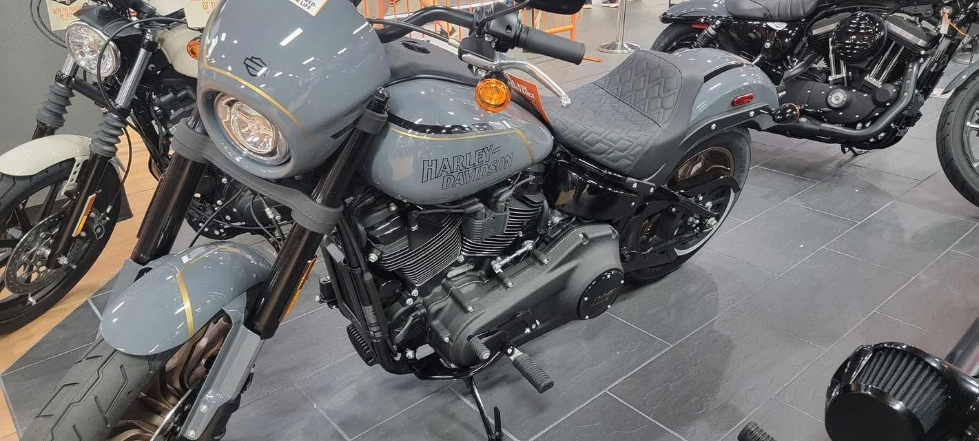 Gray motorcycle with gold accents displayed indoors among other bikes