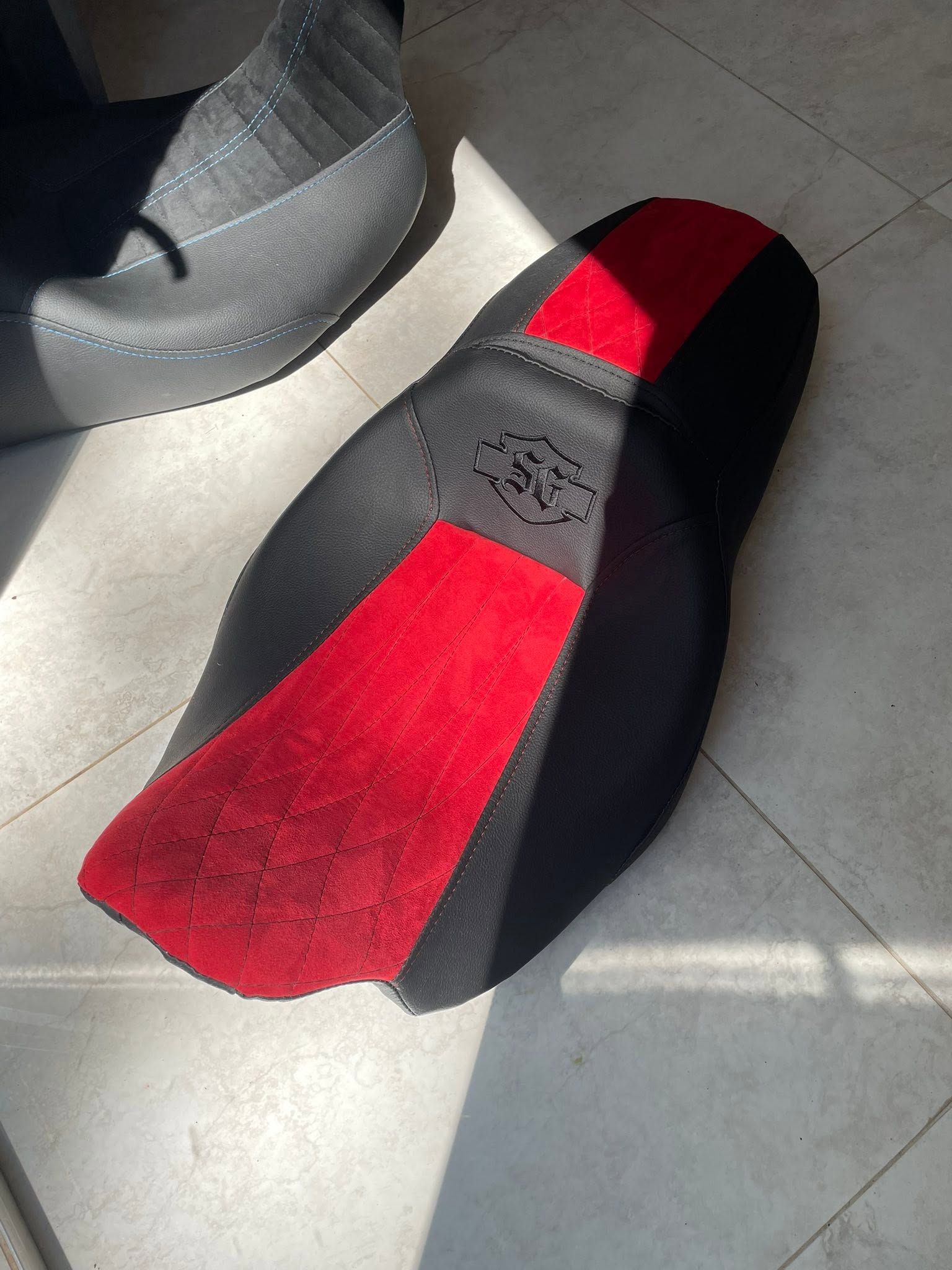 Black-and-red shoes on a tiled floor in sunlight