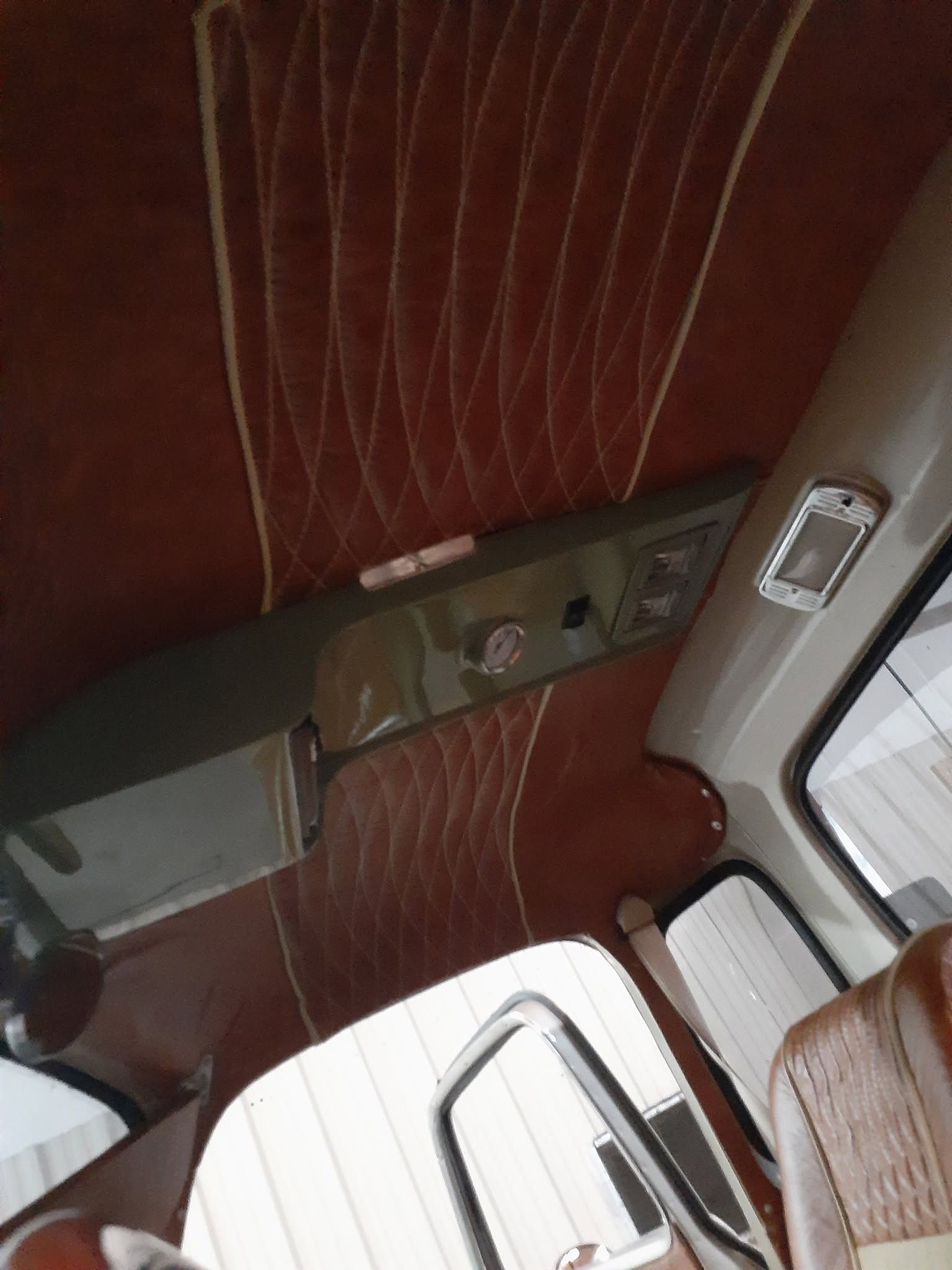 Interior of a vehicle with red quilted upholstery and windows visible at the top and bottom.