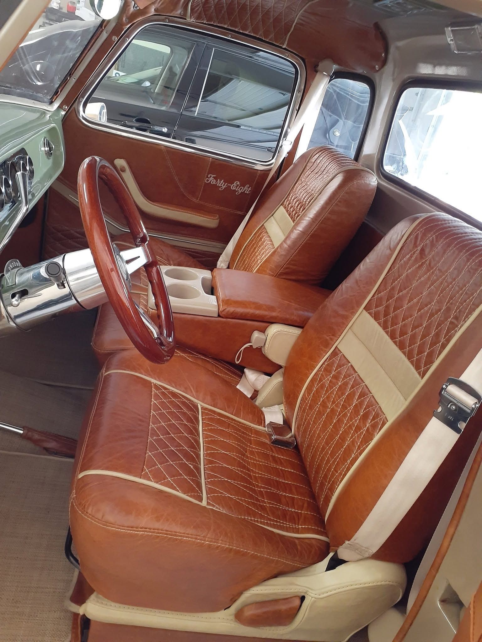 Brown and white vintage car interior with leather seats and wood steering wheel