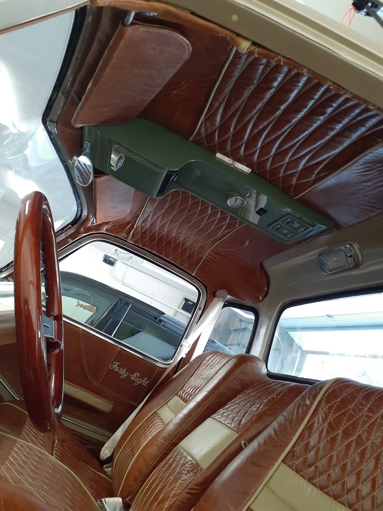 Luxury car interior with brown leather seats and quilted ceiling trim, viewed from the back seat