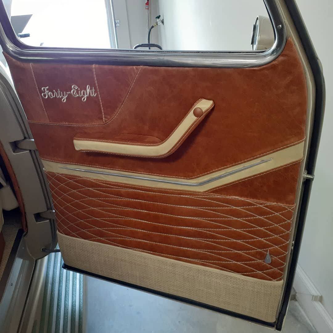 Airplane door panel with orange-brown and beige stitching, featuring a built-in handle and window above.