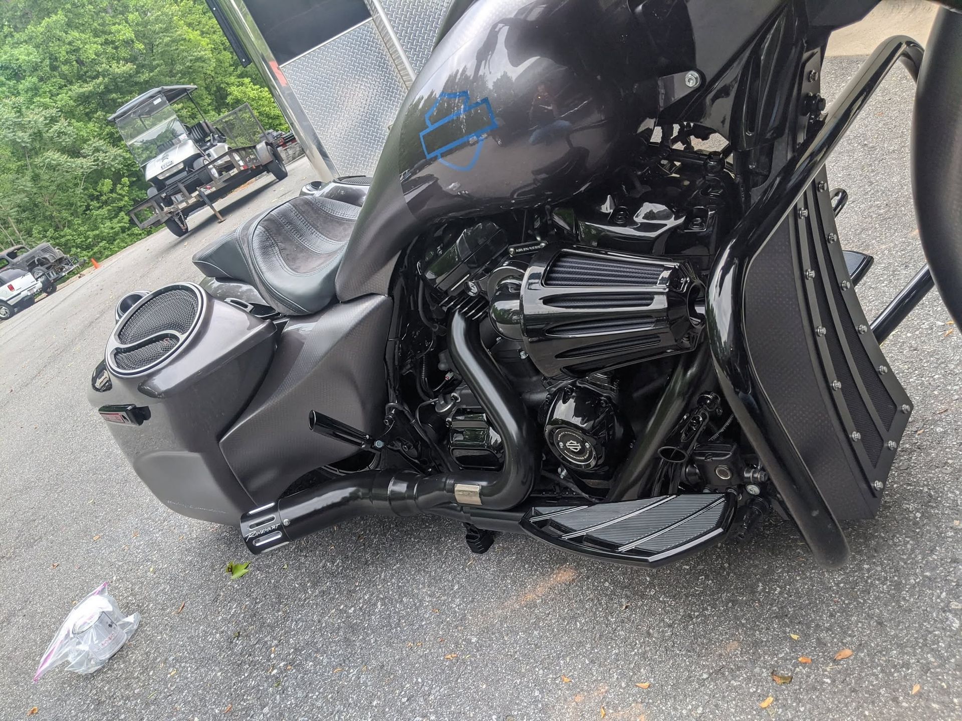 Black touring motorcycle parked on pavement, with a low seat and front fairing near a building.